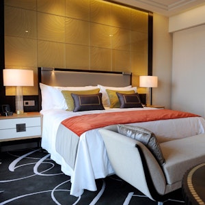 Das undatierte Symbolfoto zeigt ein Hotelzimmer mit Doppelbett, Teppichboden und einem Tisch mit roten Tulpen in einer weißen Vase.