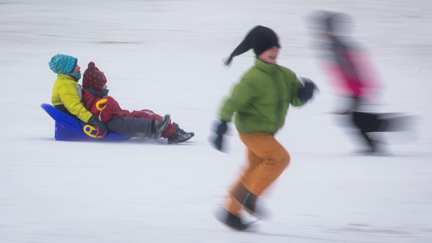 Kinder fahren mit Schlitten und rennen durch den Schnee.