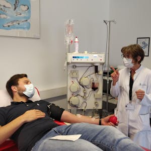 Einer der ersten Spender ist Jan K. Die Mitarbeiterin des Blutspendedienstes am Universitätsklinikum Bonn Heike Brüssler erklärt dem wieder genesenen Covid-19-Patienten den Ablauf der Plasmaspende.